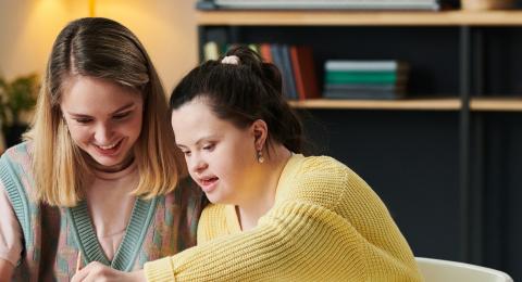 A girl with down syndrome paints a watercolor with a friend or mentor