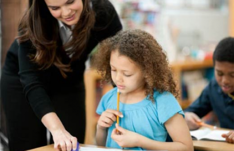 child in classroom getting help from a teacher